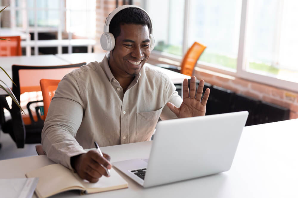 Homem negro na frente sentado na frente do laptop com fone de ouvido, estudando online nos cursos do Blog Udemy,