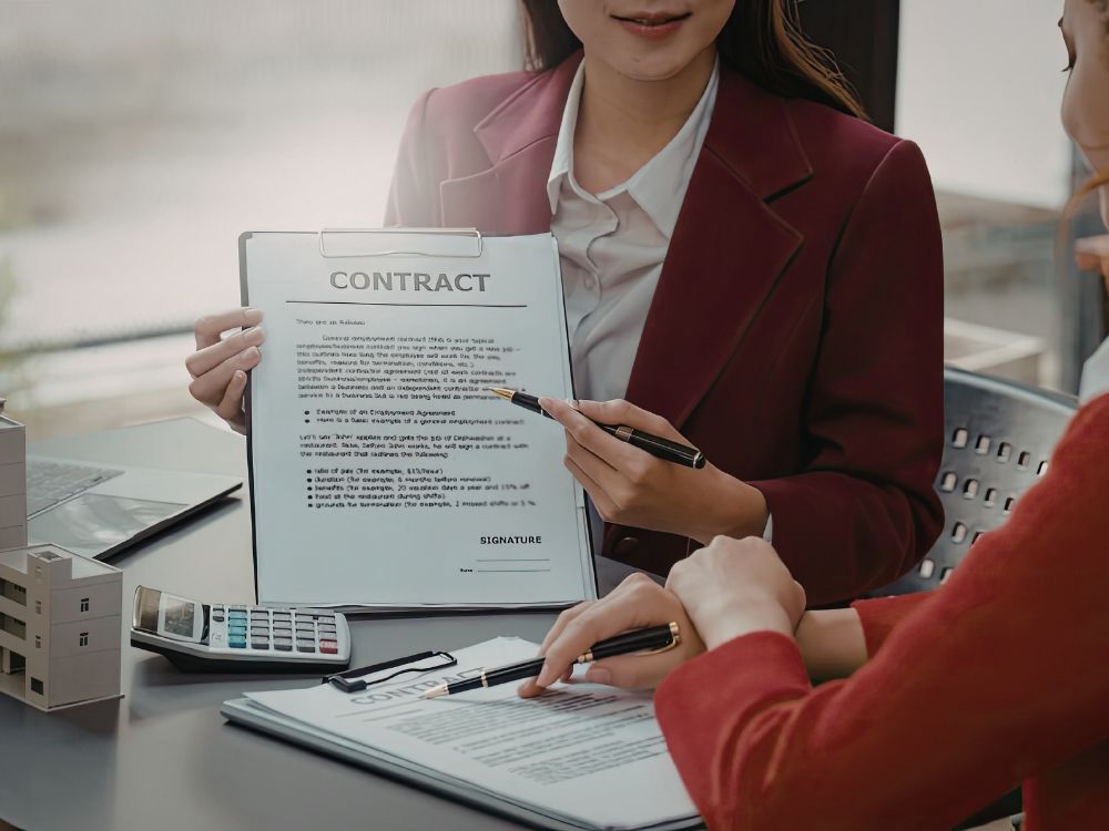 Profissional apresentando contrato a termo em prancheta para cliente, destacando cláusulas antes da assinatura do documento.